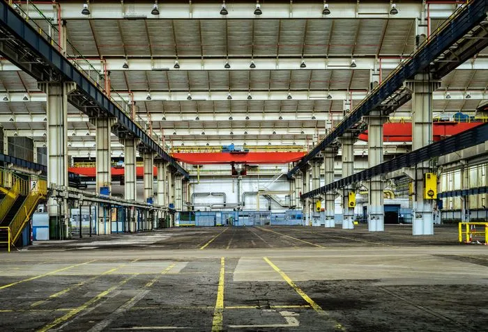 Industrial warehouse interior with overhead cranes, steel beams and skylights